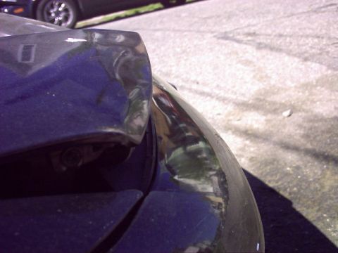 1997 Ford Probe - The rear corner of a vehicle shows damage and wear on the bumper and body panel.