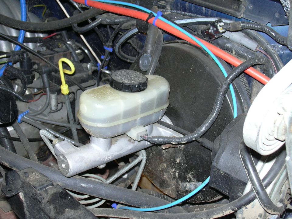 Ford logo on brake master cylinder, surrounded by engine wiring and brake lines