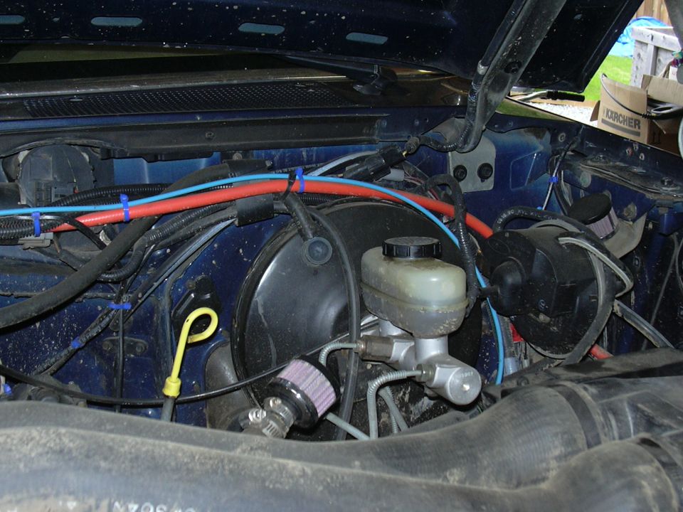 Blue engine bay with brake master cylinder, vacuum booster, and red/blue hoses