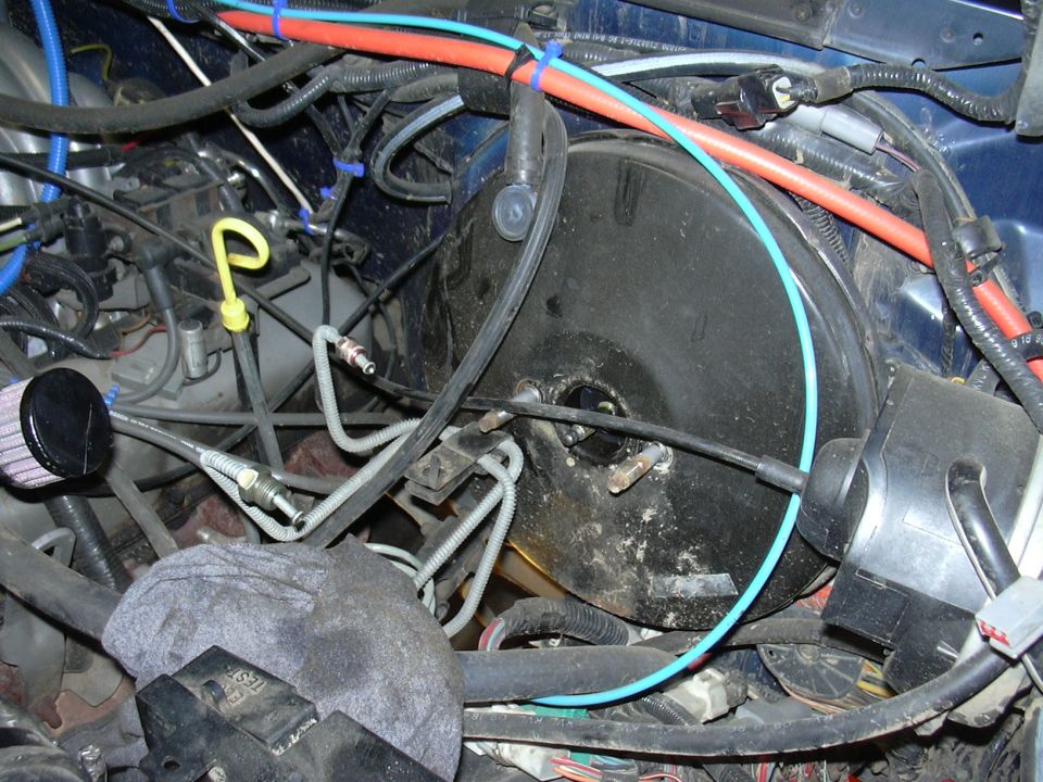 Engine bay showing brake booster, master cylinder, and various hoses and wires