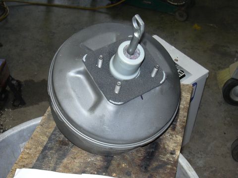 1991 Ford Bronco - Brake booster assembly resting on wood planks in a workshop.