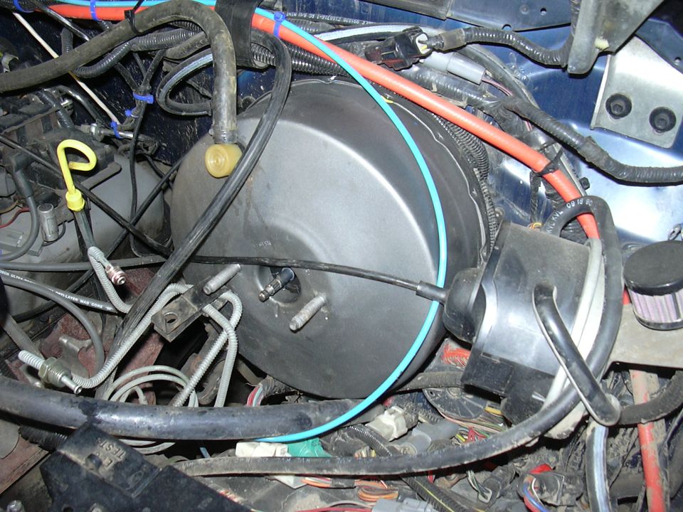 Engine bay with brake booster, master cylinder, and wiring harness. Blue paint visible