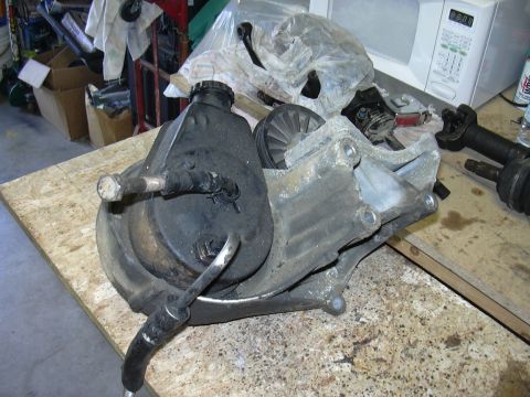 1991 Ford Bronco - A used power steering pump assembly, including the pulley and mounting bracket, sits on a workbench.