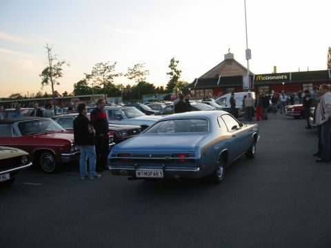 1992 Ford Crown Victoria - A blue coupe is parked at a car meet with other vehicles and people gathered around.
