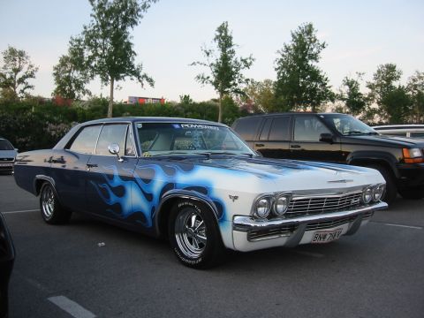 1992 Ford Crown Victoria - A classic Chevrolet Impala, customized with a striking blue flame paint job, is seen in a parking lot.