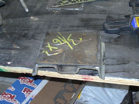 1991 Ford Bronco - A rusty rectangular sheet-metal fabricated part with a channel/lip bent along the lower edge, marked with yellow paint pen, sitting on a sc…