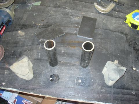 1991 Ford Bronco - Two rubber bump stops and metal tubes are laid out on a workbench, suggesting preparation for automotive repair or fabrication.