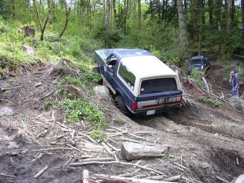 1991 Ford Bronco - A Ford Bronco navigates a challenging off-road course with steep inclines and debris.