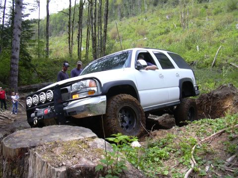 1991 Ford Bronco - A white SUV is shown maneuvering through a challenging off-road course with steep inclines and obstacles.