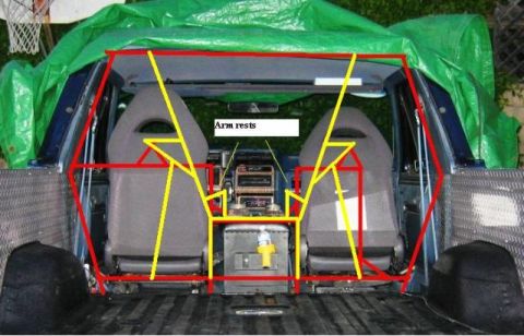 1985 Ford Bronco - The interior of a pickup truck is visible, showing the seats and dashboard with a green tarp covering the roof.