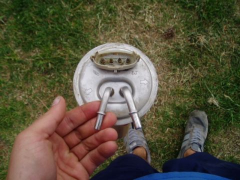 1990 Ford Bronco - A person holds a fuel pump assembly, likely for a Ford vehicle, against a grassy background.