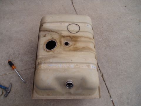 1990 Ford Bronco - A tan fuel tank, likely for a vehicle, rests on a concrete surface next to tools.