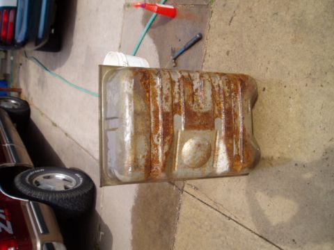 1990 Ford Bronco - A heavily rusted fuel tank sits on a concrete surface, possibly undergoing cleaning or repair.