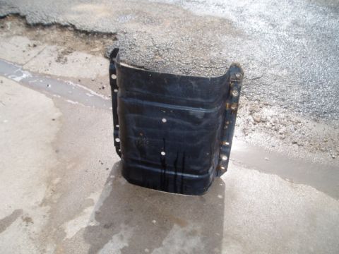 1990 Ford Bronco - A black metal fuel tank is shown from the front, resting on a concrete surface.