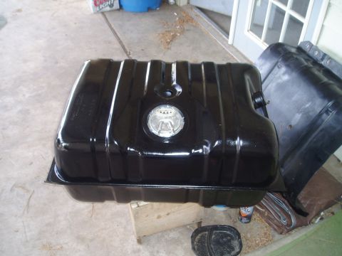 1990 Ford Bronco - A black metal fuel tank sits on a wooden block, with another part to its right.