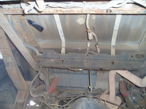 1990 Ford Bronco - The underside of a vehicle reveals a rusty frame, suspension components, and fuel lines, with no clear year identification.
