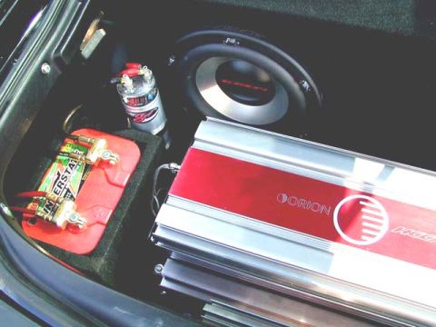 1996 Ford Probe - Close-up of car audio components including a battery, capacitor, subwoofer, and amplifier.