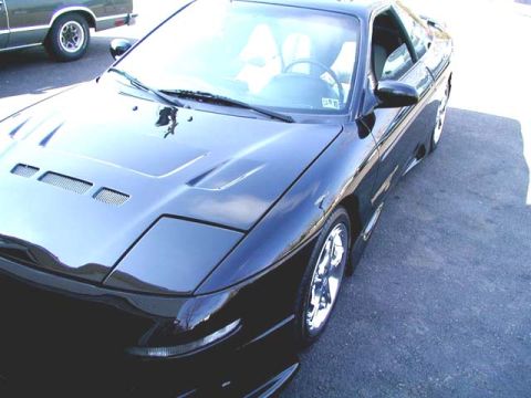 1996 Ford Probe - A black sports coupe is parked on asphalt, with another vehicle visible to the left.