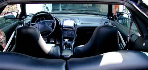 1996 Ford Probe - The interior of a black convertible is shown, leather seats and an aftermarket stereo system.
