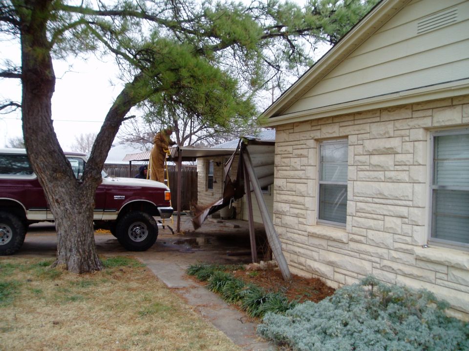 Maroon and white 1990 Ford Bronco parked next to a house with a person on a ladder