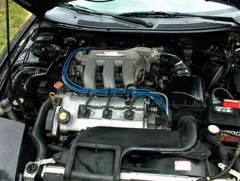 1994 Ford Probe - The engine bay of a car is shown with the hood open, revealing the engine components and wiring.