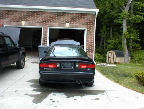 1994 Ford Probe - Rear view of a black 1994 Ford Probe GT parked in front of a garage, with another vehicle to its left.