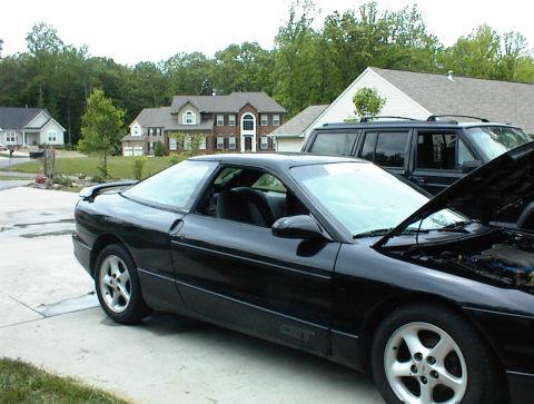 1994 Ford Probe - A black 1994 Ford Probe GT is parked in a suburban driveway with its hood up, next to an SUV.