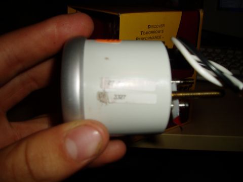 1990 Ford Bronco - A white oil pressure gauge with a silver bezel is held in a hand, with wires and a yellow box visible.