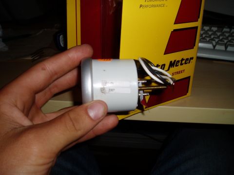 1990 Ford Bronco - A white Auto Meter oil pressure gauge is shown, held in a hand with its wiring exposed.