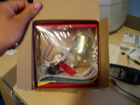 1990 Ford Bronco - An oil pressure gauge and sender unit are packaged inside a box, with a hand holding the box lid.