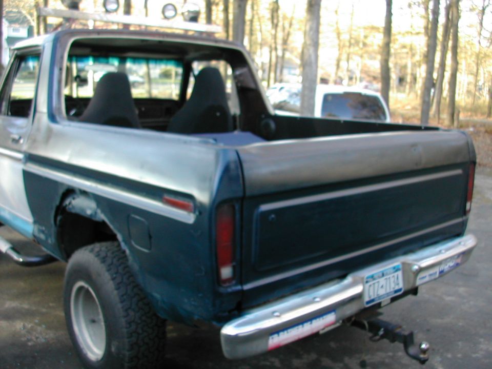 1978 Ford Bronco rear view, showing custom roof rack, interior seats, and aftermarket bumper stickers