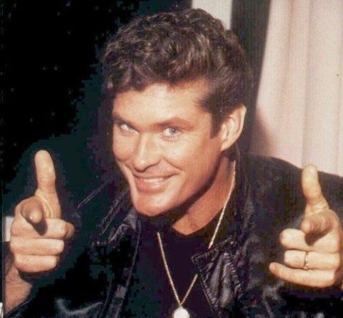 1999 Ford Taurus - A man with a confident smile and a leather jacket points his fingers forward, looking directly at the camera.