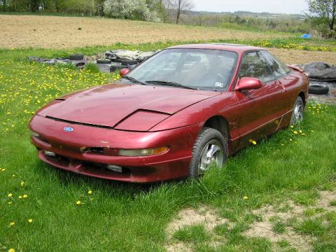 1994 Ford Probe - A red coupe with pop-up headlights sits in a field of grass and dandelions.