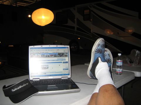 1968 Ford Mustang - A laptop is open on a table, with a person's feet resting on another table in front of it. An RV is visible in the background.
