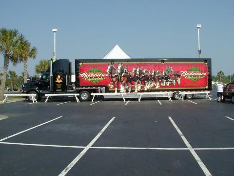 1994 Ford Probe - A Budweiser Clydesdales semi-truck and trailer is parked in a lot under a clear sky.