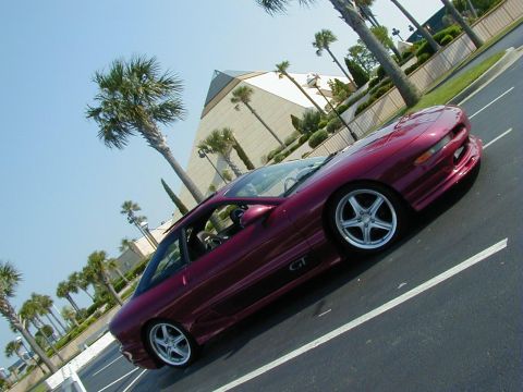 1994 Ford Probe - A maroon Ford Probe GT is parked in a lot with palm trees and a pyramid-shaped building in the background.