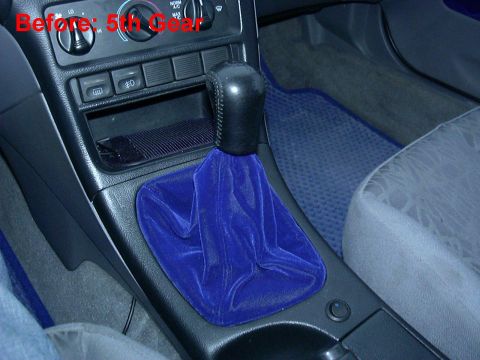1995 Ford Probe - A close-up of a car's interior focuses on a blue velvet shifter boot and the surrounding dashboard controls.