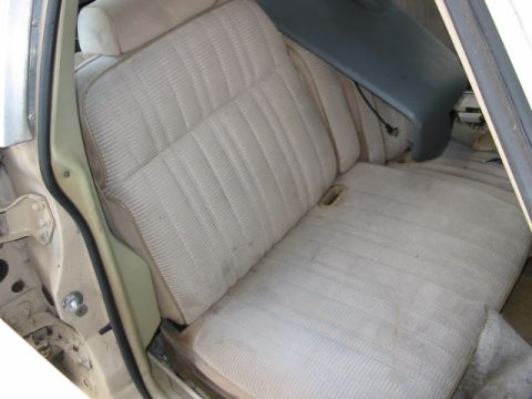 1985 Ford LTD Crown Victoria - Interior view of car seats with beige fabric upholstery and a dark blue trim piece visible.