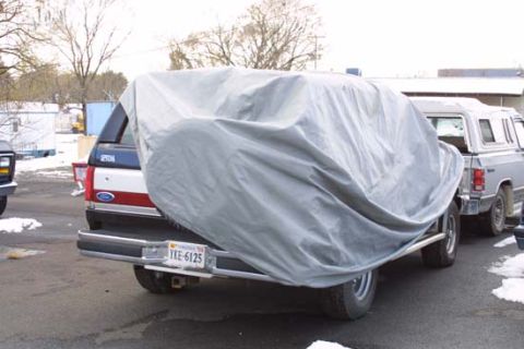 1989 Ford Bronco - A Ford Bronco is covered by a gray car cover, parked next to another vehicle.