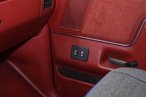 1989 Ford Bronco - Close-up of the red interior door panel, fabric inserts and power window controls, consistent with a 1989 Ford Bronco.