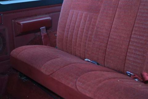 1989 Ford Bronco - Close-up of the interior of a vehicle, showing the red fabric bench seat and door panel.