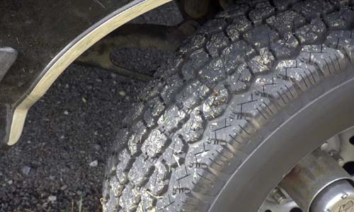 Close-up of all-terrain truck tire tread with gravel stuck in the lugs