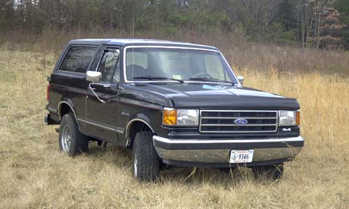 Black late-1980s Ford Bronco 4x4 front three-quarter view in a dry grass field