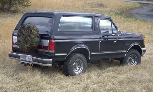 Black late-1980s Ford Bronco rear three-quarter view with camo spare tire cover