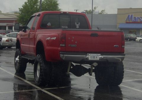 1989 Ford Bronco - This red Ford F-350 pickup truck is shown from the rear, equipped with oversized tires.