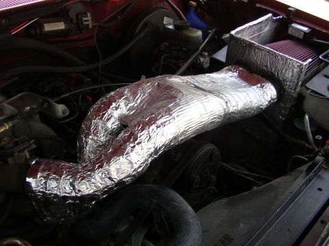 1995 Ford Bronco - Close-up of an engine bay showing a custom intake system with a red air filter and silver-wrapped tubing.