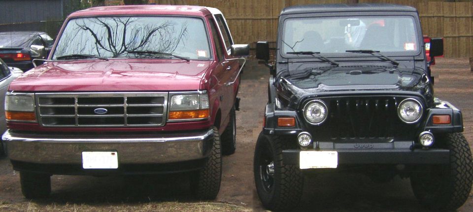 Front view of a 1995 Ford Bronco next to a black Jeep Wrangler