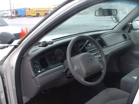 1999 Ford Crown Victoria - The interior of a 1999 Ford Crown Victoria police car is visible, the dashboard, steering wheel, and seats.
