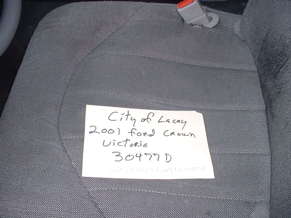 Gray fabric car seat with a note that says 'City of Lacey 2001 Ford Crown Victoria 30477D'