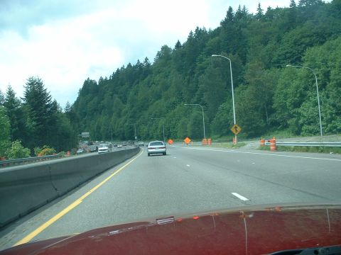 1999 Ford Crown Victoria - A white 1999 Ford Crown Victoria travels down a highway surrounded by trees and construction zones.